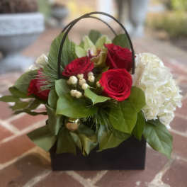 Basket arrangement with red roses and white hydrangea