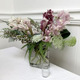 Pink and burgundy orchids arranged in a clear glass vase