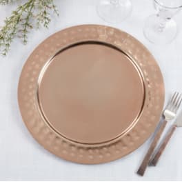Rose-gold charger plate on a white table setting with glassware and cutlery