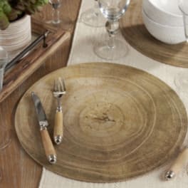 Wooden charger plates with silverware and glassware on a table setting