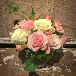 Pink and cream roses arranged in a clear glass vase