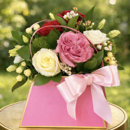 Pink and white roses in a pink gift bag with a ribbon