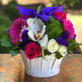 Mixed bouquet in a white basket with pink, white, and purple flowers