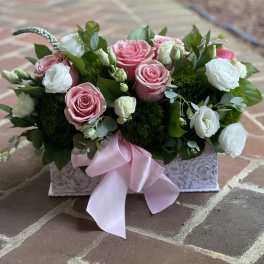 Pink and white roses in a decorative box with a pink ribbon