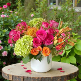 Bright mixed bouquet of pink, orange, and green flowers in a white vase