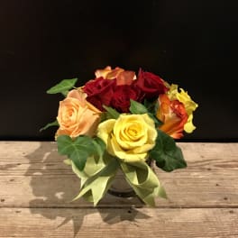 Bouquet of red, yellow, and peach roses in a glass vase