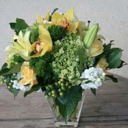 Yellow lilies and roses arranged in a clear glass vase