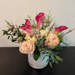 Pink calla lilies and blush roses in a white vase