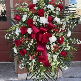 Large standing floral spray with red roses and white flowers on an easel