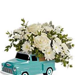 White flower arrangement in a turquoise toy truck planter