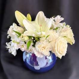 White lilies and roses arranged in a blue vase