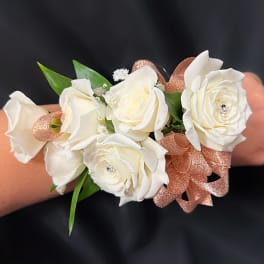White rose wrist corsage with rose-gold ribbon on a wrist