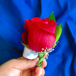 Red rose boutonniere with white ribbon and baby's breath