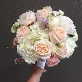 Handheld bouquet of pale pink and white roses with white blooms