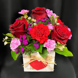 Red roses and pink carnations in a white wooden box with a red heart