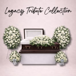 White funeral casket surrounded by white floral sprays