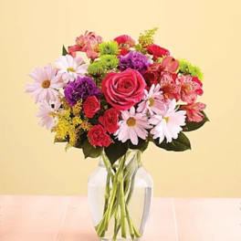 Mixed bouquet of pink, red, purple, and white flowers in a clear glass vase