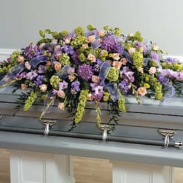 Lavender and peach floral casket spray on a gray casket