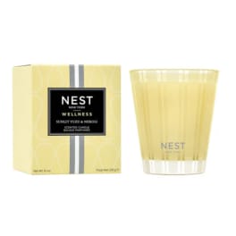 Yellow scented candle in glass holder beside matching Nest New York box