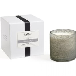 Fragranced candle in a glass holder beside its white gift box