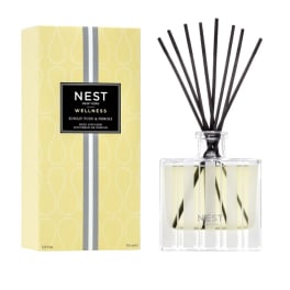 Yellow reed diffuser with black reeds beside its box