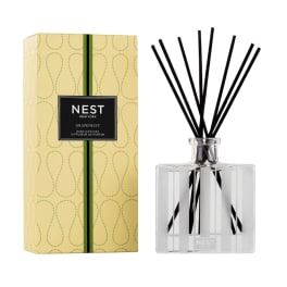 Reed diffuser with black sticks beside a yellow Nest New York box