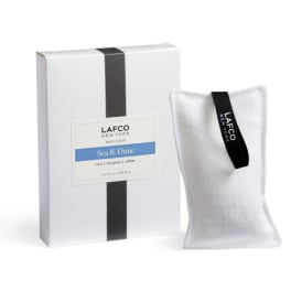 White boxed candle with a fabric sachet beside it