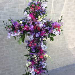 Tall floral cross arrangement in pink, purple, and white flowers