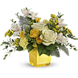 Yellow and white rose arrangement in a yellow glass vase