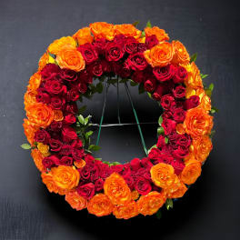 Circular wreath of red and orange roses on a stand