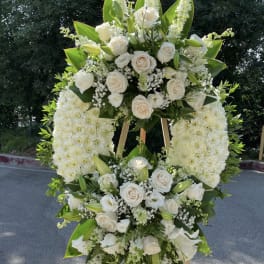 Large white floral standing spray on an easel with roses and lilies