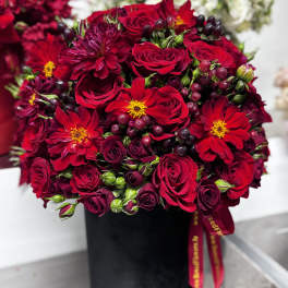 Red roses and burgundy flowers arranged in a black box