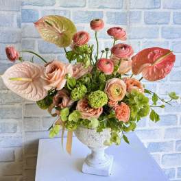 Pink and peach floral arrangement in a white pedestal vase