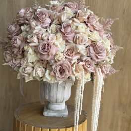 Large bouquet of blush and cream roses in a white urn vase