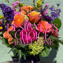 Bright jewel-tone bouquet with orange and pink roses, purple blooms, and green hydrangea.