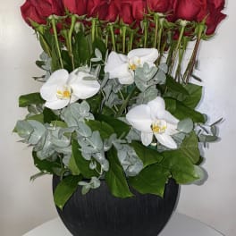 Red roses and white orchids arranged in a black vase