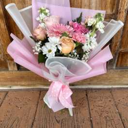 Pink and peach mixed bouquet wrapped in pastel paper with a ribbon