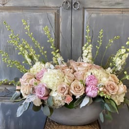 Pastel floral arrangement in a gray bowl with roses and tall white spikes