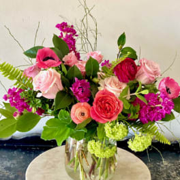 Mixed pink and red flowers arranged in a clear glass vase