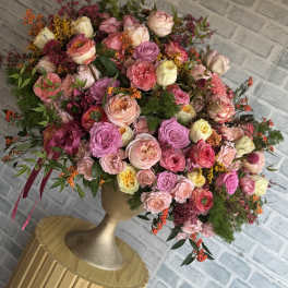 Large bouquet of pink and cream roses in a gold vase