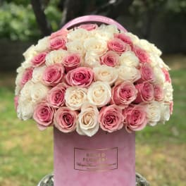 Pink and white roses arranged in a round pink hat box