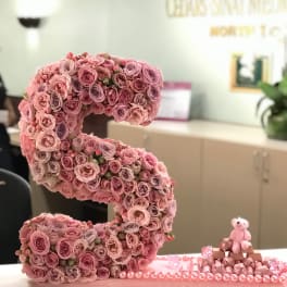 Pink rose letter display with a small teddy bear and chocolates
