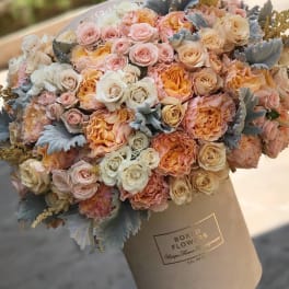 Large bouquet of blush, peach, and cream roses in a wrapped box