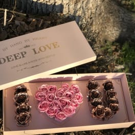 Pink rose arrangement in a heart-shaped box with gold roses on the sides
