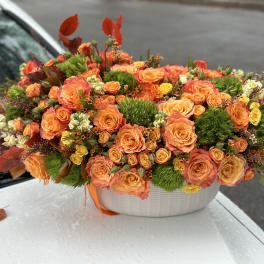 Orange rose arrangement in a white oval container