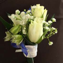White tulips and small white flowers with blue accents in a wrapped bouquet
