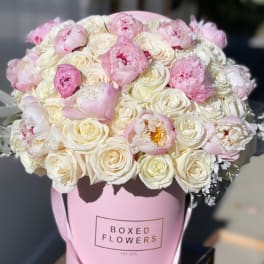 Pink and white bouquet of peonies and roses in a pink box