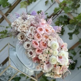 Pastel bouquet of roses, orchids, and white blooms on a mirrored stand