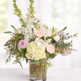 Pastel flower arrangement in a clear glass vase with white and pink blooms