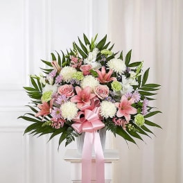 Pink and white floral arrangement with a pink ribbon in a vase